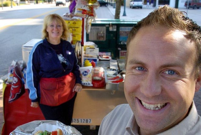 Earl Hjertstedt, owner of the Tasty Take-Out hot dog stand, with his mother and stand in the background. With chips and a drink, the meal will set you back $5. His mother, Marlene Hjertstedt, frequently operates the downtown Sarasota stand.