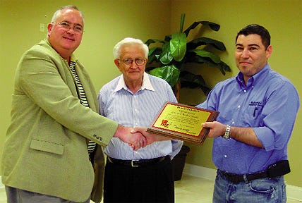 Pastor Charles Hatcher III, left, and Pastor Emeritus Elton Bernard, center, of The Pentecostals present Fred Garcia of Louisiana Roofing Supply with plaques as thanks for donating materials and labor to construct a new roof on its church, Centro de Vida, on Airline Highway in Gonzales.