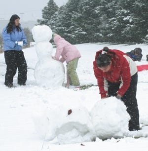 Taking advantage of a half-day of school and the snow storm that hit Monday, these kids found plenty to do. Angelica Lozano, 13 (left), and Arianna Prieto, 9, work on building a snowman while Angie Guevra, 17, (in front) rolls snow to build her snow fort. While the girls were building, the boys (in back) were bent on destruction, fighting with each other and throwing snowballs. That group included Robert Lozano, 16, Harley Lozano, 14 and Ricky Prieto.