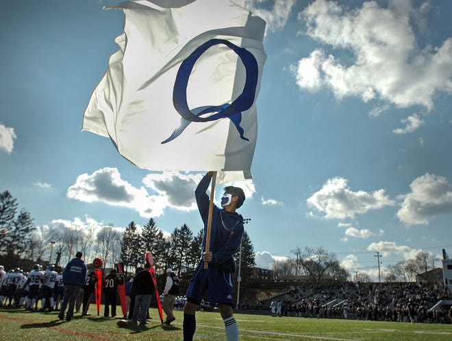 Quincy High sophomore Kevin Ung waves the school flag as his team celebrates a touchdown against North Quincy on Thanksgiving.