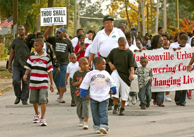 WILL DICKEY/The Times-UnionDonald Foy (center), president of the Jacksonville MAD DADS chapter, leads an anti-violence march down First Street at A. Philip Randolph Park on Saturday.