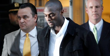 New York Giants wide receiver Plaxico Burress, second from left, is escorted from a police station in handcuffs on Monday, Dec.1, 2008, in New York. Lawyer Benjamin Brafman says Burress plans to plead not guilty to a weapon possession charge during a Monday afternoon court appearance. Burress accidentally shot himself at a Manhattan nightclub Friday evening.