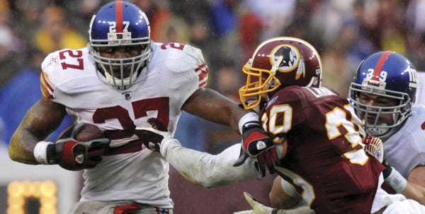 Giants running back Brandon Jacobs (27) runs by Redskins safety LaRon Landry (30) as Giants fullback Madison Hedgecock tries to block during the fourth quarter Sunday.