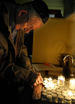 At a memorial service at the Chabad Center of Sudbury, Elliot Winer of Sudbury lights a candle in memory of Rabbi Gavriel Holzberg and his wife, Rivka, who were kiiled in the Chabad-Lubavitch Jewish Center in Mumbai, India.
