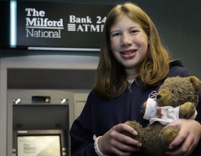 Allison Fishlock, 14, of Hopedale holds her teddy bear at Milford National Bank on Thursday. She had lost the bear and it was confiscated by police who had responded to a call at the bank about a suspicious backpack.