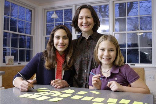 Rosemarie Fabien and her girls Carolyn Normile, 13, left, and Grace Normile, 9, are shown with with pieces of paper with names for their annual Secret Santa ritual, in Wynnewood, Pa. Families, friends and companies looking to stretch scarce budgets without stomping all over holiday cheer are turning to Secret Santa, charitable donations and similar group gift exchanges in these sour economic times.