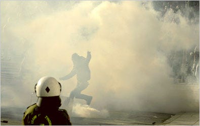 A protester kicked a tear-gas canister back toward police officers on Tuesday in Athens on a fourth day of violence set off by the killing of a teenager by the police.