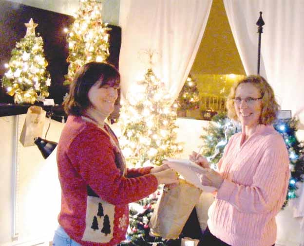 Large crowds braved winter temperatures to take part in the Galva Art Council’s Holiday Tour of Homes and Festival of Mini-Trees Sunday. Mini-Tree Festival organizer Dee Bersell, left, and arts council officer Nancy Anderson prepare to draw names of the winners of the donated mini-trees and wreaths. Anderson’s entry was the People’s Choice winner in the Festival of Mini-Trees.