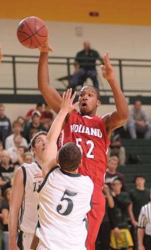 Holland's Josh Weatherspoon (52) puts up a shot while Zeeland West's Bryan Gezon (5) tries to block him Friday night at Zeeland West High School.