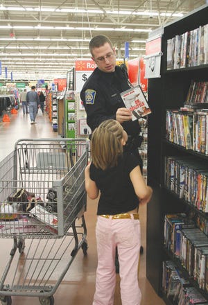 Monmouth Police Officer Bill Benson helps Briana Noles pick out a DVD for her mother.