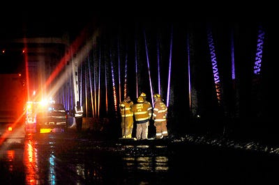 Cooper County firefighters stand near the site of a crash Tuesday on Eastbound I-70 on the Missouri River bridge where a man involved in the crash jumped over the bridge wall into the river to avoid a passing truck he thought was going to hit him.