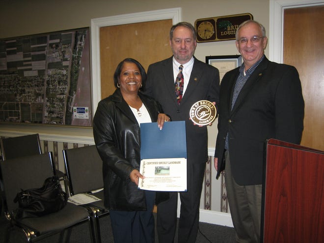 Laverne Sorrell, left, receives an historic marker from Mayor Joey Normand, center, and Jim Rills. Laverne and her husband, James, now operate the Romper Room Day Care in the building once known as the Herbert Jackson Home. Their property is one of 16 historic sites honored in ceremonies earlier this month.