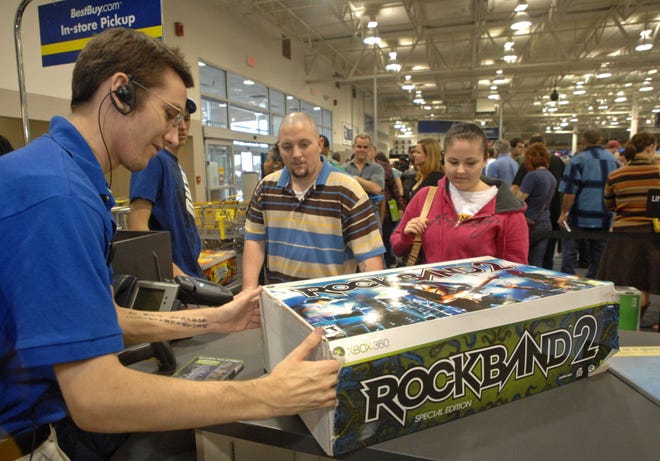 Best Buy sales clerk Dan Voight, left, assists Chris and Sharon Knowles in replacing a scratched CD in the "Rock Band 2" game they had previously purchased. They were among hundreds of shoppers returning, exchanging or taking advantage of sale prices at the popular electronics retailer. (John Carrington/Savannah Morning News)