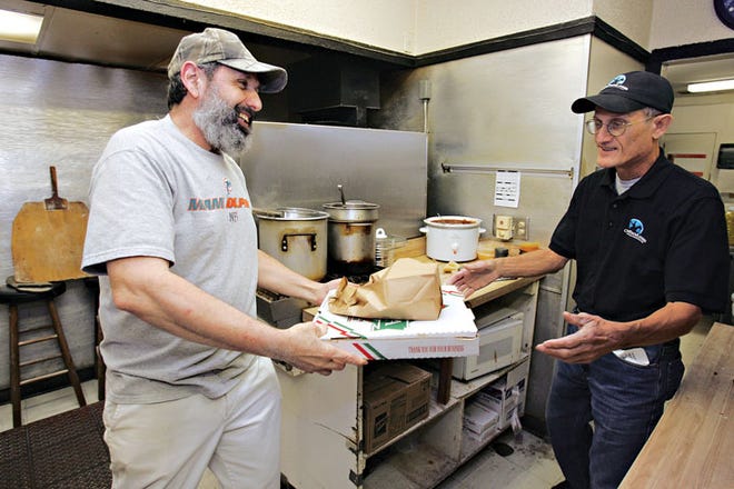 Al DiFeo, the owner of Abio's, left, passes an order to Joe Cariglio, a delivery driver for Ocalafood.com at Abio's Pizza on State Road 200 in Ocala, Fla. on Dec. 22. Ocalafood.com outsources
delivery for local restaurants.