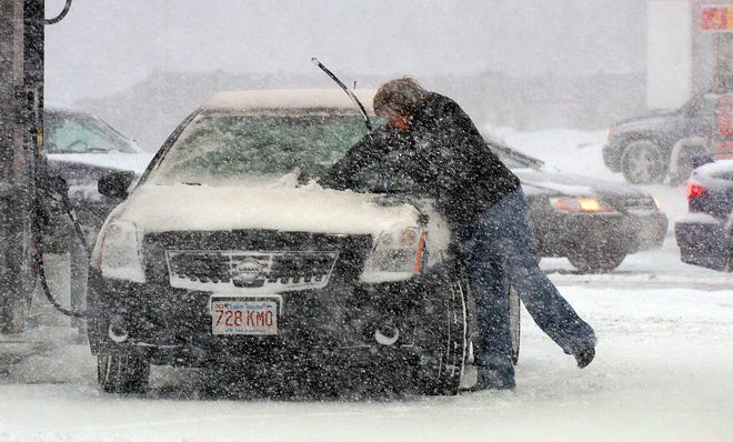 A driver tries to keep her windshield wipers clear of ice and snow as wind-blown snow covers the South Shore.