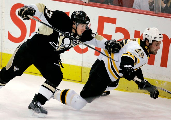 Pittsburgh Penguins' Sidney Crosby, left, works against Boston Bruins' Mark Stuart (45) during the first period of Tuesday's game in Pittsburgh.