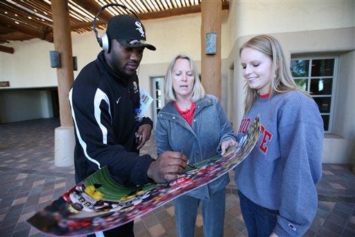 Ohio State running back Chris "Beanie" Wells, left, signs posters for fans Cathy Thomas of New Albany, Ohio, center, and her daughter Lindsay Michalski of Midland Mich., right, following a press conference Thursday, Jan. 1, 2009 in Scottsdale, Ariz. Ohio State will face Texas in the Fiesta Bowl NCAA college football game on Jan. 5. (AP Photo/Aaron J. Latham)