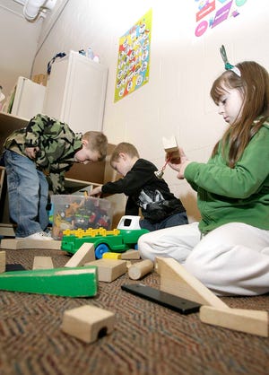 Hayden Miller, left, and Collin Carter look through a box of toy trucks for their favorites as Abbey Dunn gives some thought to a creative way to utilize the bell in constructing a block building.