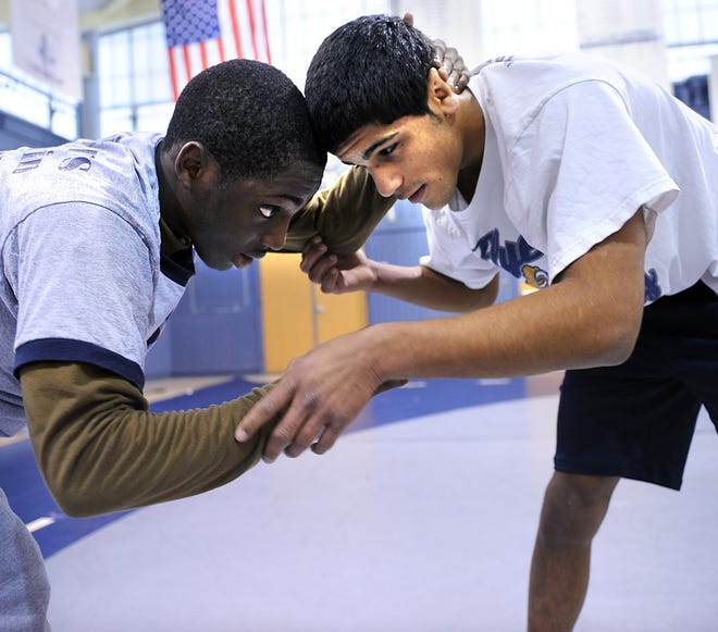 Framingham wrestler Walter Pope (right) works out with Herry Joubert during a recent practice. Pope was moved into a foster home prior to his freshman year of high school, but after struggling for a couple of years dedicated himself to school and will attend the Naval Academy.