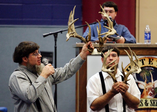 Crisp Miller, left, an auctioneer with Steve Chutt Auctioneers, holds up the antlers of a buck whose semen was being auctioned during the Top 30 Whitetail extravaganza held at the Capitol Convention Center Friday.