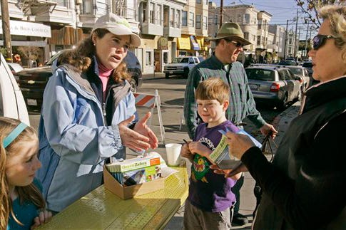 Cynthia Hogan, second from left, sells a Green Zebra entertainment coupon book for a school fund-raiser Saturday, Jan. 10, 2009, in San Francisco. Beside Hogan are her daughter Audrey Platt, left, son Philip, and husband Meserve Platt, background right. Hogan pulled her daughter and son out of Catholic school last year, when she started feeling the squeeze of a recession that had just begun. "We just couldn't keep writing the check. It was killing us," she says.