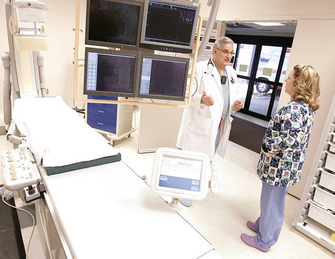 Dr. Ahmed Sabe, director of Mercy Medical Center’s Heart Center, chats with Natasha Benson, a cardiac intervention tech, in the hospital’s catheterization lab.