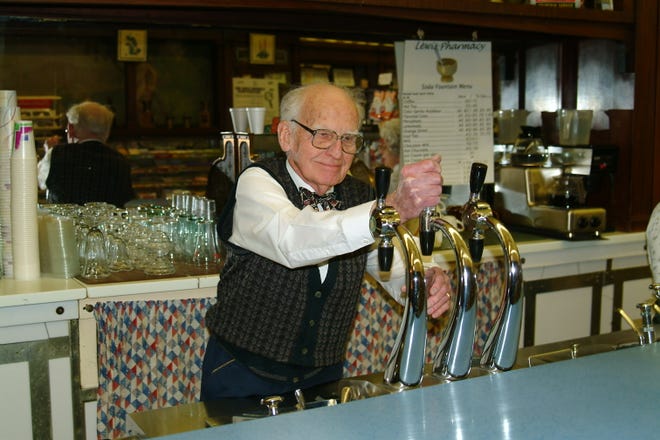 Long-time local business owner and Canton historian Ed Lewis prepares a soft drink from a soda fountain that has been at Lewis Pharmacy since the business was first built in 1915 as Gustine's Drug Store. The woodwork and tiling in the store are original as well.