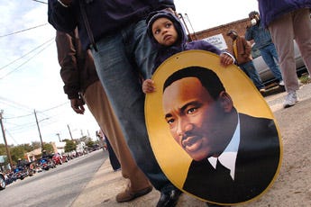 18 month old Henry Gregory IV holds a photo of Dr. Martin Kuther King Jr. Monday afternoon along Castle Street as he watches the Martin Luther King Jr. Parade go by. More than a thousand people gathered along Castle Street to help honor the memory of Dr. King.