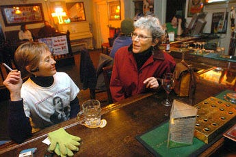 Lynn Harris (left) and former City Council member Pat Delair talk the Goat and Compass on Tuesday. The site was one of several MoveOn inauguration parties around Wilmington, but the inclement weather kept turnouts low.