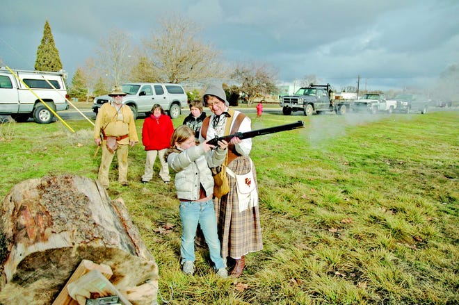Sarah Wilhelm, 11, a fifth-grader at Montague Elementary School, fires a black powder rifle with the help of Linn "Little Finger" Lewellyn, a member of the Siskiyou Mountain Men, while mountain man Mike "Twoball" Dooley and Wilhelm's mother and brother, Laura Allen and Daniel Wilhem, look on.