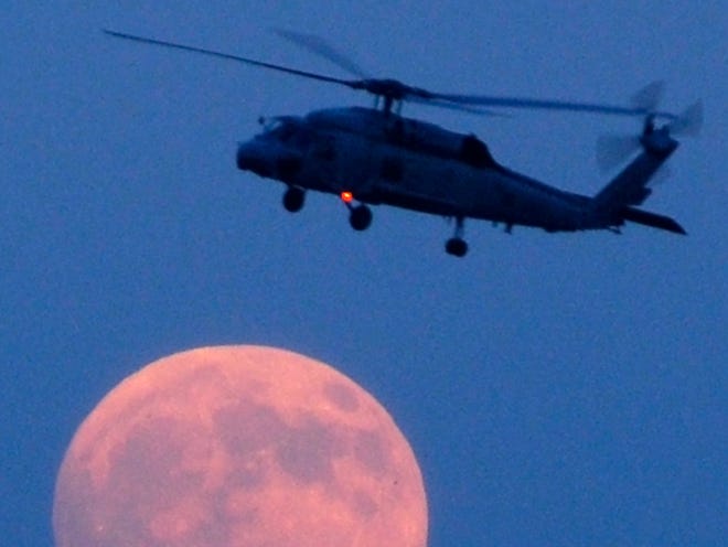JON M. FLETCHER/The Times-Union A SH60 helicopter with the HS-3 Tridents flies in front of the moon in this 2007 photo following a training exercise on the St. Johns River.