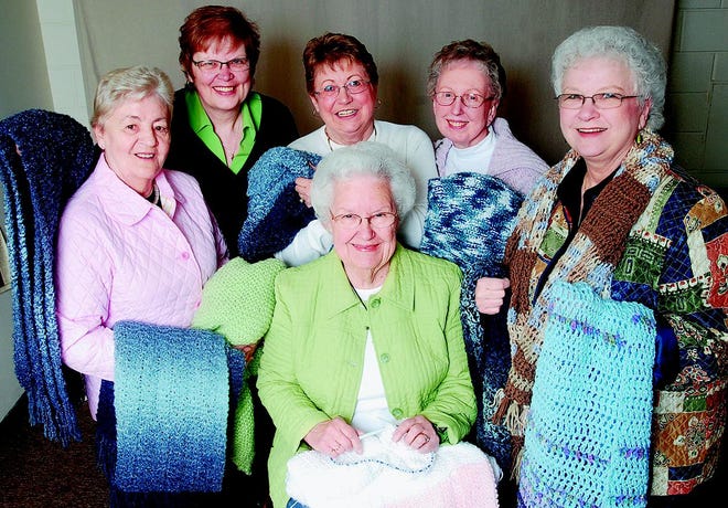 Clockwise from left, members of the Comfort Shawl Ministry, Betty Herrmann, Jeanne Almasy, Ann Tully, Sharon Lang, Lil Garrow, and Eileen Olloff pose with some of their knitting works.