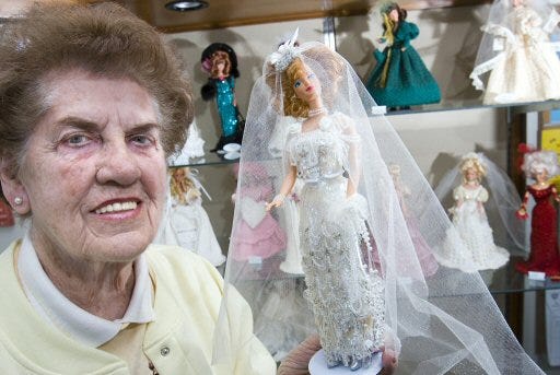 Adele Williams shows off a jeweled Edwardian bride. It took her about a year to make the dress. Williams has 17 crocheted dresses displayed on Barbie dolls at the new Dunnellon Library until the end of February.