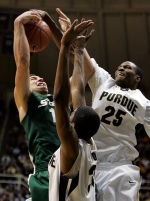 Michigan State center Goran Suton, left, is fouled by Purdue forward JaJuan Johnson, right, as Suton shoots over Purdue's E'Twaun Moore during the second half of an NCAA college basketball game in West Lafayette, Ind., Tuesday, Feb. 17, 2009. Purdue defeated Michigan State 72-54. (AP Photo/Michael Conroy)