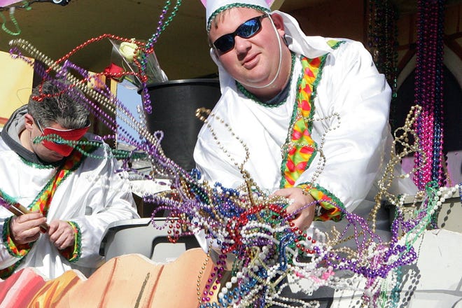 A float rider with the Krewe of Chronos tosses beads to paradegoers Sunday in Thibodaux.
