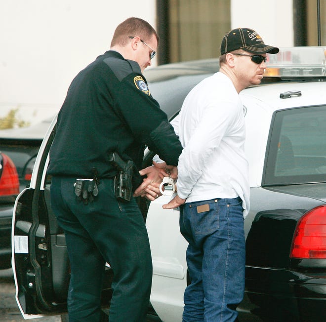Police arrest one of two men Monday at a Motel 6 at Interstate 35 and SE 44 in Oklahoma City. PHOTO BY STEVE GOOCH, THE OKLAHOMAN