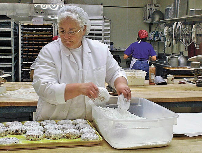 Debbie Maleport, working in the Soo Co-Op Bakery puts powdered sugar on a paczek at the bakery this morning. Bakeries around town, and the country, loaded up their shelves with the Polish delights. Maleport said the Co-op made 2,184 paczki for today (an above-average output), and sold nothing but paczki.