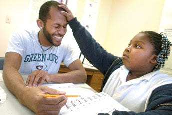 UNCW student Darryl Harrison, left, shares a fun moment while teaching reading to Taleeyah Perry at the Community Campus at Hillcrest Wednesday, February 11, 2009.