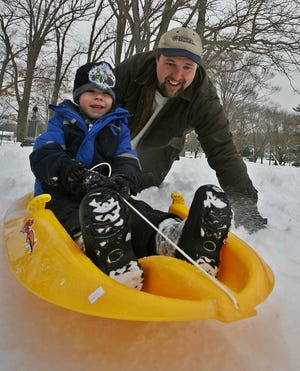 Tom King of Hanson pushes son Michael, 5, down the hill as they sled in the Whitman Town Park Monday afternoon.