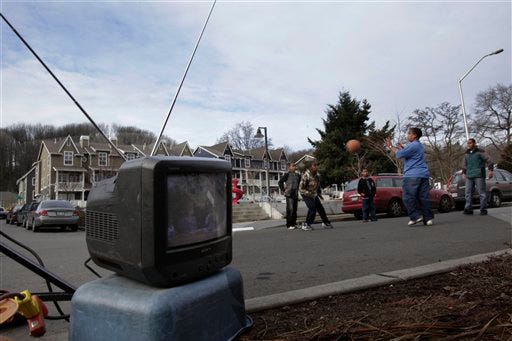 Children play with a ball near a television set equipped with a traditional "rabbit ears" antenna that was set up to monitor a live broadcast, Tuesday, Feb. 17, 2009, in Seattle. Tuesday would have been the day when analog TV signals were turned off, and viewers who lack cable or satellite would have to tune in to digital signals. But when funding ran out for coupons to subsidize TV converter boxes, Congress became concerned that viewers wouldn't be ready, and hurriedly passed a bill to delay the deadline to June 12.