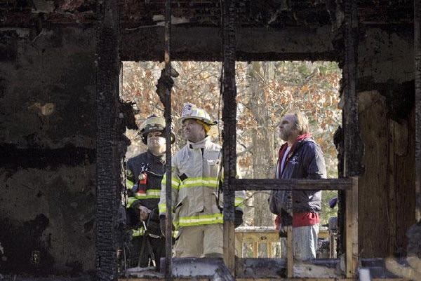 Cotuit Fire Chief Chris Olsen, center, firefighter Ty Anderson, and homeowner Frederick Newman survey the damage from an early morning fire yesterday at 10 Bramblebush Drive.