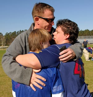 WILL DICKEY/The Times-UnionTate Loftis (left) and Alex Thomas get a hug from Alex's dad, Scott Thomas, after their game in the Down Syndrome Association Soccer League Feb. 21 at Patton Park.