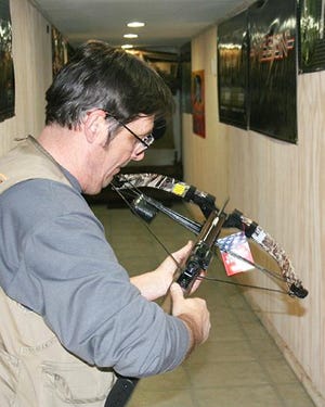 Steve Wowianko, Mackinaw Outfitter bow tech, flips off the safety and prepares to fire a crossbow. He has put on many similar demonstrations since the DNR expanded crossbow hunting opportunities just over a week ago.