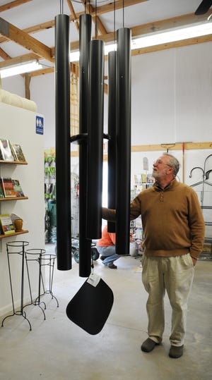 George Gunter, owner of Gunter’s Garden World, rings the 18-foot wind chimes at his business.