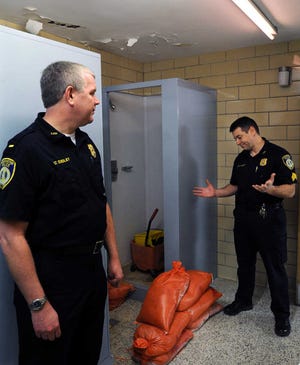 Lt. Jeff Dudley, left, and Sgt. Mark Amico stand in the nonfunctioning shower area in the men’s bathrooms at the Leominster police station, where raw sewage has backed up several times.