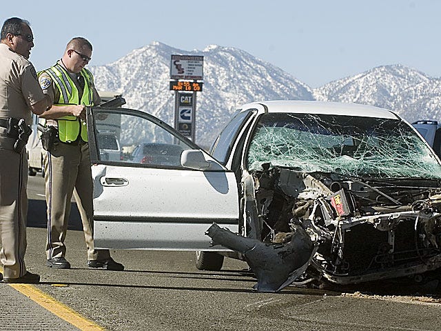 California Highway Patrol officers look over a damaged Honda on the Interstate 15 at the Joshua Street Exit Monday morning.