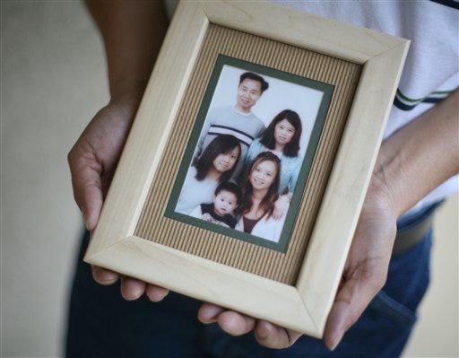In a Monday, March 16, 2009, file photo, Brian Tzeo holds a family picture of himself, top left, his wife Lisa Phan, back right, daughters Pauline Chao, front left, 18, Melanie Saephan, front right, 20, and son Cody Tzeo, 3. Brain Tzeo's family was killed Thursday, March 12, 2009 at their home in Conover, N.C. A man suspected in the slayings killed himself and his girlfriend after a police chase in Utah that ended with his car in flames, authorities said Wednesday, March 18, 2009. (AP Photo/Jason E. Miczek, File)