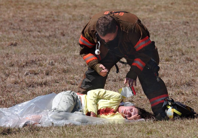 TERRY DICKSON/The Times-UnionA Glynn County firefighter checks the injuries to Regina Driscoll in her role as a passenger whose plane crashed at the airport.