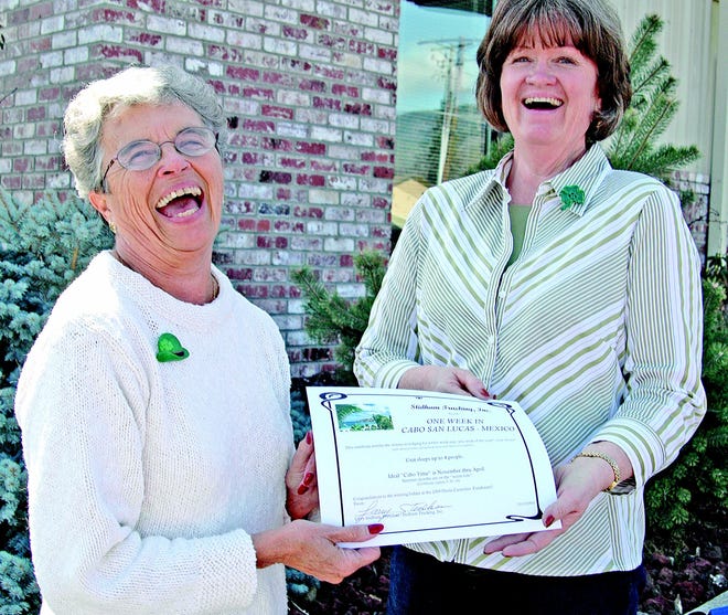 Frances Stidham, left, and Kim Bridwell share a laugh Tuesday at Stidham Trucking, Inc. in Yreka as Stidham presents a certificate good for one week's stay in Cabo San Lucas, Mexico.