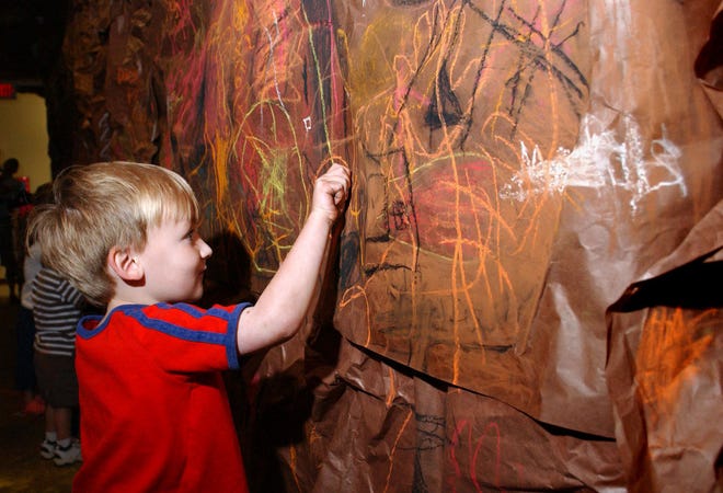 TERRY DICKSON/The Times-UnionPre-K student Wyatt Dalton, 4, draws on the brown paper walls of a "cave" created Friday in a hallway at Golden Isles Elementary for a daylong arts festival at the school.